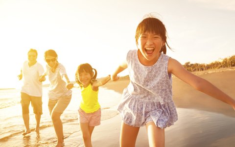 family running on beach at sunset