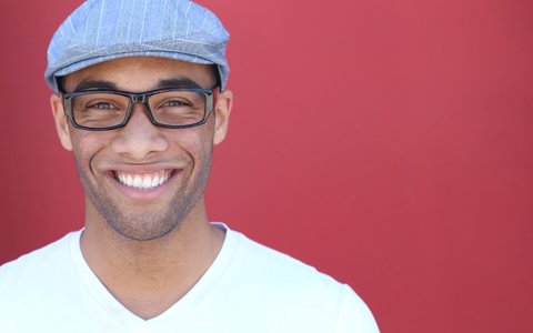 man smiling in front of red wall