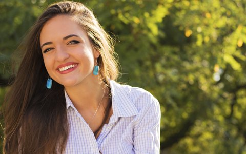 brunette with earings smiling outdoors