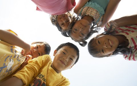 children standing over camera looking down