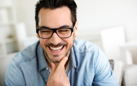 man with glasses smiling and looking down