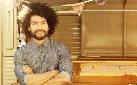 man with afro outside of trailer smiling