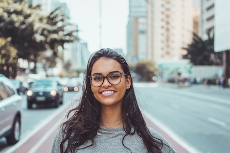 teen wearing glasses in street smiling